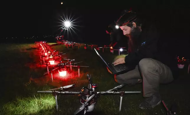 In this handout photo Gabor Vasarhelyi, physicist and researcher of the Department of Biological Physics at Eötvös Loránd University, is using his computer to set a swarm of 100 quadcopters to fly autonomously during an experiment near Budapest, Hungary, Thursday, Oct. 21, 2021. (AP Photo/HO/Eotvos Lorand University)