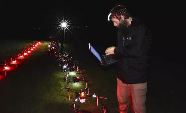 In this handout photo Gabor Vasarhelyi, physicist and researcher of the Department of Biological Physics at Eötvös Loránd University, is using his computer to set a swarm of 100 quadcopters to fly autonomously during an experiment near Budapest, Hungary, Thursday, Oct. 21, 2021. (AP Photo/HO/Eotvos Lorand University)