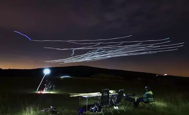 This handout photo taken with long exposure shows a researcher of the Eötvös Loránd University observing the flight of a flock of autonomous drones during an experiment near Budapest, Hungary, Thursday, Oct. 21, 2021. (AP Photo/HO/Eotvos Lorand University)