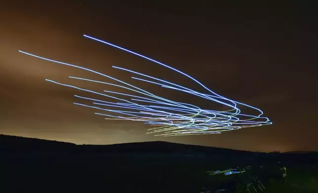 This handout photo taken with long exposure shows a researcher of the Eötvös Loránd University observing the flight of a flock of autonomous drones during an experiment near Budapest, Hungary, Thursday, Oct. 21, 2021. (AP Photo/HO/Eotvos Lorand University)