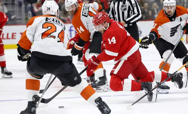 Detroit Red Wings center Tyler Motte (14) tries to keep control of the puck against Philadelphia Flyers defenseman Nick Seeler (24) and center Sean Couturier (14) during the first period of an NHL hockey game Wednesday, Dec. 18, 2024, in Detroit. (AP Photo/Duane Burleson)