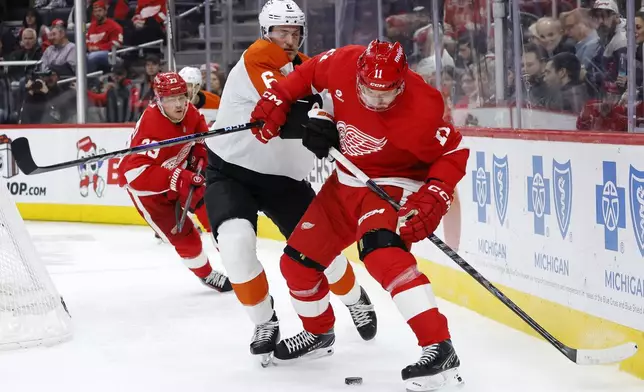 Philadelphia Flyers defenseman Travis Sanheim (6) and Detroit Red Wings right wing Vladimir Tarasenko (11) battle for a loose puck during the first period of an NHL hockey game Wednesday, Dec. 18, 2024, in Detroit. (AP Photo/Duane Burleson)