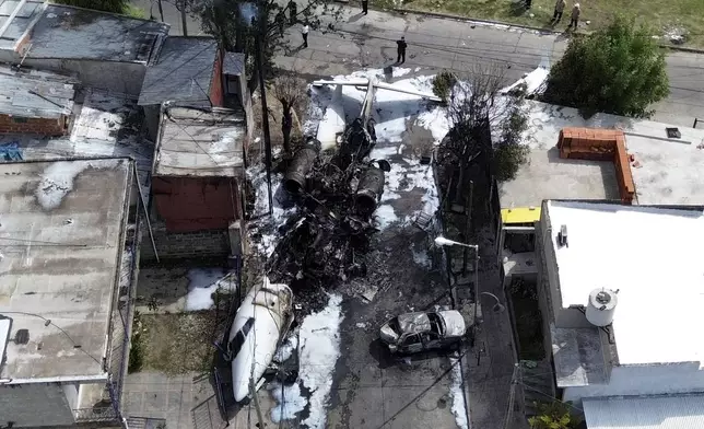 The wreckage of a private plane lays next to homes after crashing near the airport in San Fernando on the outskirts of Buenos Aires, Argentina, Wednesday, Dec. 18, 2024. (AP Photo/Natacha Pisarenko)