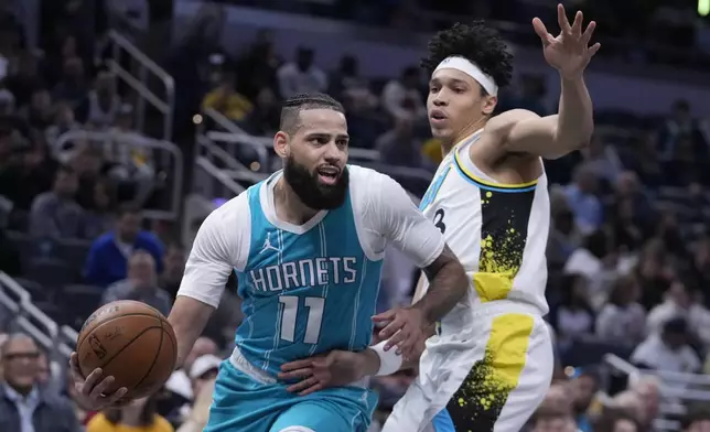 Charlotte Hornets' Cody Martin (11) looks to pass the ball against Indiana Pacers' Enrique Freeman, right, during the first half of an NBA basketball game, Sunday, Dec. 8, 2024, in Indianapolis. (AP Photo/Darron Cummings)