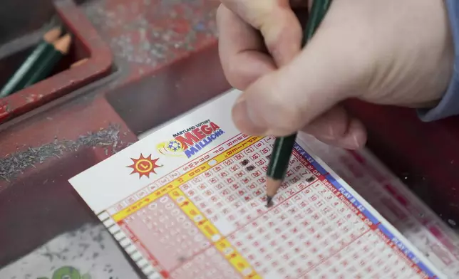 A person fills out a Mega Millions play slip ahead of Friday's Mega Millions drawing of $1.15 billion, Thursday, Dec. 26, 2024, in Baltimore. (AP Photo/Stephanie Scarbrough)