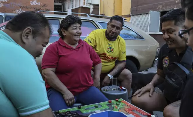 From left, Salvador Espinosa, Rosa Espinosa, Diego Castillo, Erik Cisneros and Ulises Tiscareño share a joke while playing poleana, a board game invented in prison in Mexico City, Sunday, Dec. 8, 2024. (AP Photo/Ginnette Riquelme)