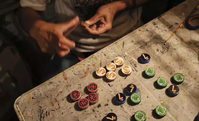 Dana Lopez sands a wooden token for poleana, a board game invented in prison, in his workshop in Mexico State, Mexico, Friday, Oct. 25, 2024. (AP Photo/Ginnette Riquelme)