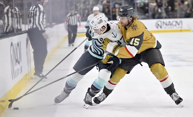 Seattle Kraken center Yanni Gourde (37) and Vegas Golden Knights defenseman Noah Hanifin (15) battle for the puck during the first period of an NHL hockey game Saturday, Dec. 21, 2024, in Las Vegas. (AP Photo/David Becker)