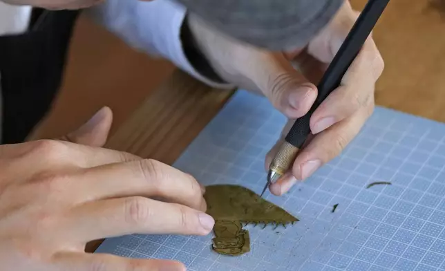 Japanese leaf-cutting artist, who goes by the name Lito, uses a design knife, cutting a leaf for his work, during an interview in Tokyo Wednesday, Nov. 27, 2024. (AP Photo/Shuji Kajiyama)