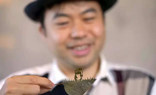 Japanese leaf-cutting artist, who goes by the name Lito, looks at his freshly cut work featuring a frog with an umbrella, during an interview in Tokyo Wednesday, Nov. 27, 2024. (AP Photo/Shuji Kajiyama)