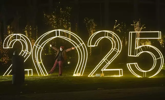 An Egyptian poses in front of New Year decorations in Cairo, Egypt, Tuesday, Dec. 31, 2024. (AP Photo/Amr Nabil)