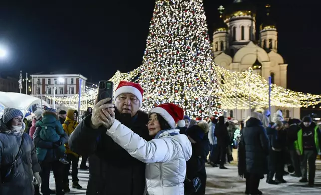 A couple make a selfie as other people gather in the center of the Russian far east port of Vladivostok, Russia, Tuesday, Dec. 31, 2024, to celebrate the new year 2025. (AP Photo)