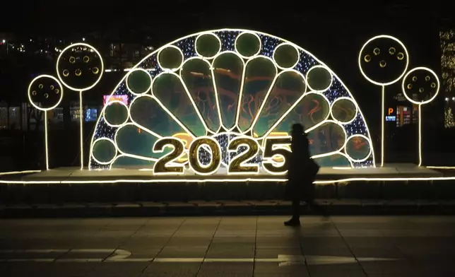 A woman walks near an illuminated decoration on New Year's Eve in Seoul, South Korea, Tuesday, Dec. 31, 2024. (AP Photo/Lee Jin-man)