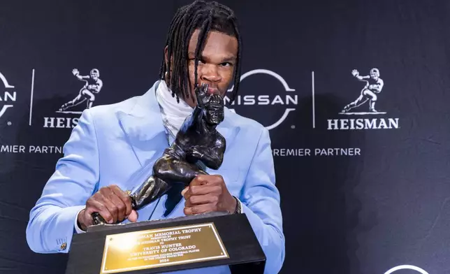 Heisman Trophy winner Travis Hunter, of Colorado, kisses the trophy at a press conference after the awards ceremony, Saturday, Dec. 14, 2024, in New York. (AP Photo/Corey Sipkin)