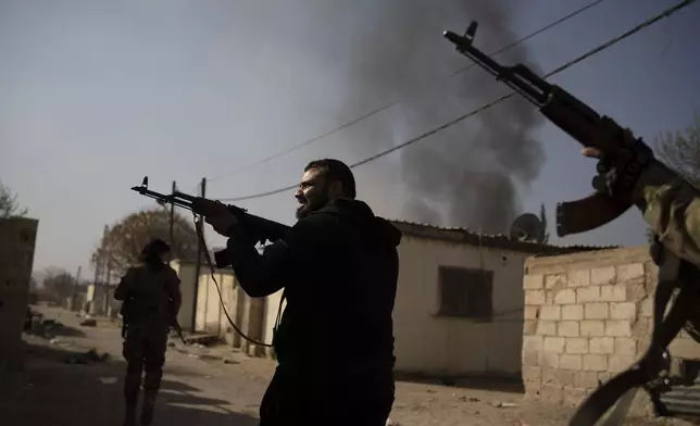 Syrian fighters aims their weapons in direction of suspected looters at a residential complex of former Bashar Assad's military officers at the village of Husseiniyeh, in the outskirts of Damascus, Syria, Sunday, Dec. 15, 2024. (AP Photo/Leo Correa)