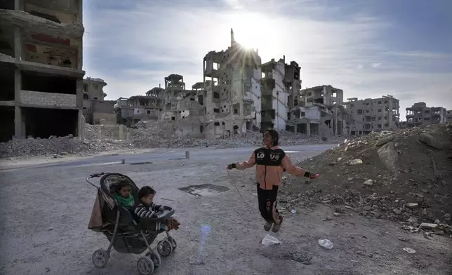 A young Palestinian girl plays at a street between destroyed buildings which were not only destroyed during the civil war they were also demolished by the government or stripped by thieves, at the Palestinian refugee camp of Yarmouk, outside Damascus, Syria, Saturday, Dec. 14, 2024. (AP Photo/Hussein Malla)