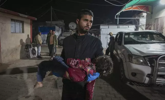 A dead child is carried into the Al-Aqsa Martyrs hospital in Deir al-Balah after an Israeli army strike in the Bureij refugee camp, central Gaza Strip, Saturday Dec. 14, 2024.(AP Photo/Abdel Kareem Hana)