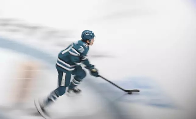 San Jose Sharks center Macklin Celebrini (71) controls the puck against the Calgary Flames during the third period of an NHL hockey game Saturday, Dec. 28, 2024, in San Jose, Calif. (AP Photo/Eakin Howard)