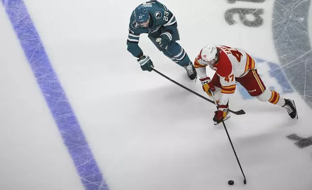 Calgary Flames center Connor Zary (47) controls the puck against San Jose Sharks right wing Barclay Goodrow (23) during the third period of an NHL hockey game Saturday, Dec. 28, 2024, in San Jose, Calif. (AP Photo/Eakin Howard)