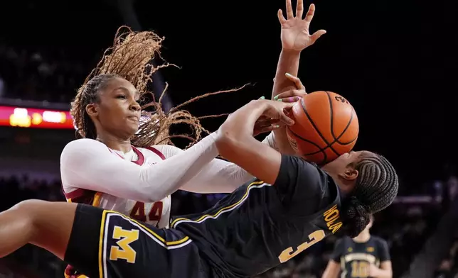 Southern California forward Kiki Iriafen, left, blocks a shot by Michigan guard Mila Holloway during the first half of an NCAA college basketball game, Sunday, Dec. 29, 2024, in Los Angeles. (AP Photo/Mark J. Terrill)