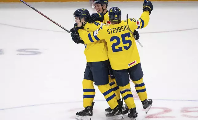 Sweden forward Otto Stenberg (25) and teammate Rasmus Bergqvist (2) celebrate Axel Sandin-Pellikka's (4) hat-trick goal during third period IIHF World Junior Hockey Championship preliminary round action against Slovakia, in Ottawa, Thursday, Dec. 26, 2024. (Spencer Colby/The Canadian Press via AP)