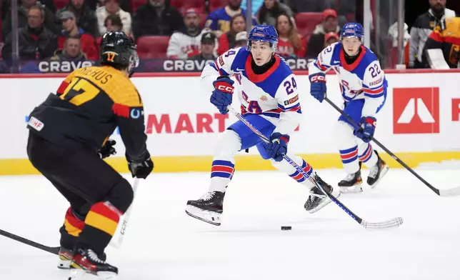 USA defenceman Cole Hutson (24) moves the puck up the ice as Germany defenceman Lua Niehaus (17) moves in the defend during third period IIHF World Junior Hockey Championship preliminary round action in Ottawa on Thursday, Dec. 26, 2024. (Sean Kilpatrick/The Canadian Press via AP)