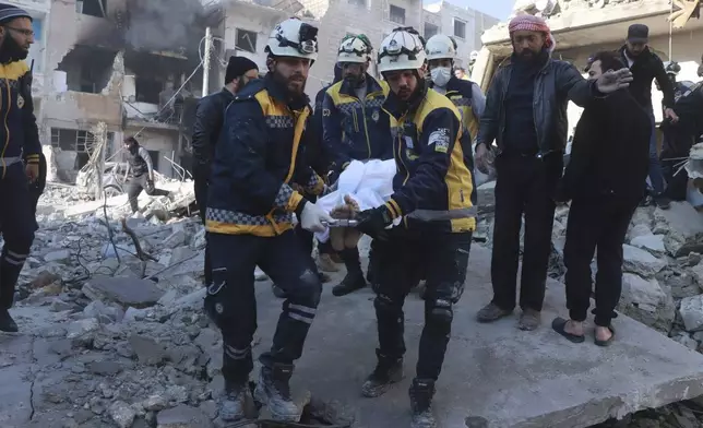 This photo provided by the Syrian Civil Defence White Helmets, which has been authenticated based on its contents and other AP reporting, shows Syrian White Helmets civil defence workers carry a victim after the Syrian government forces hit Idlib city, Syria, Monday, Dec. 2, 2024. (Syrian Civil Defence White Helmets via AP)