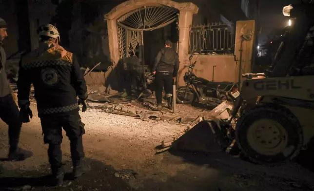 Residents inspect the site of an air strike in Idlib, Syria, Sunday Dec. 1, 2024. Government airstrikes in Idlib killed at least three civilians, including two children, and wounded 11 others, said the Syrian Civil Defense, known as the White Helmets, which operates in opposition-held areas. (AP Photo/Omar Albam)