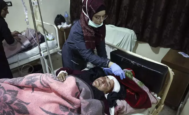 A nurse attends to an injured woman in Idlib, Syria, Sunday Dec. 1, 2024. Government airstrikes in Idlib killed at least three civilians, including two children, and wounded 11 others, said the Syrian Civil Defense, known as the White Helmets, which operates in opposition-held areas. (AP Photo/Omar Albam)