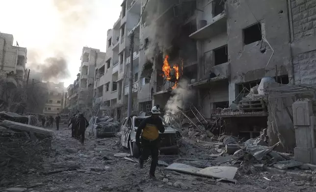 This photo provided by the Syrian Civil Defence White Helmets, which has been authenticated based on its contents and other AP reporting, shows a Syrian White Helmet civil defence worker running in a destroyed neighborhood after the Syrian government forces hit Idlib city, Syria, Monday, Dec. 2, 2024. (Syrian Civil Defence White Helmets via AP)