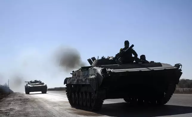 Syrian opposition fighters drive a seized seized Syrian army armoured vehicle near the town of Khan Assubul, Syria, southwest of Aleppo, Sunday, Dec. 1, 2024. Syrian opposition insurgency launched a campaign on Wednesday with a two-pronged attack on Aleppo and the countryside around Idlib.(AP Photo/Ghaith Alsayed)