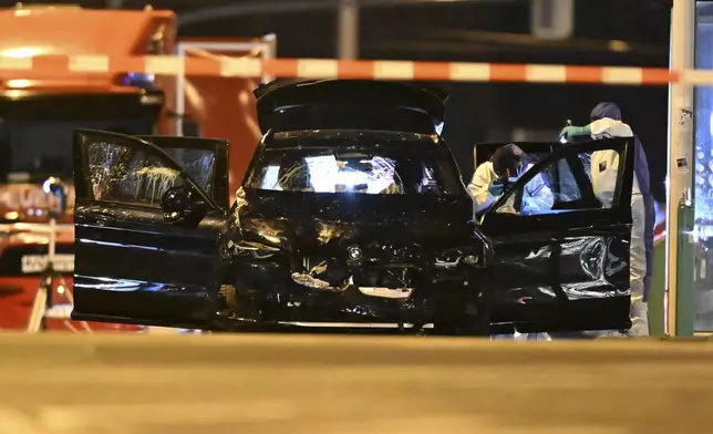 Forensics work on a damaged car sitting with its doors open after a driver plowed into a busy Christmas market in Magdeburg, Germany, early Saturday, Dec. 21, 2024. (Hendrik Schmidt/dpa via AP)