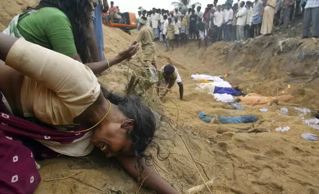 Relatives of victims who were killed by Tsunami waves grieve at the site of a mass burial in Cuddalore, India, Monday, Dec. 27, 2004. (AP Photo/Gurinder Osan, File)