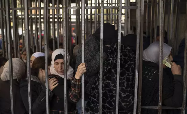 People line up to buy bread in a bakery near Bab Touma, a neighborhood of the Old City of Damascus, Syria, Saturday, Dec. 21, 2024. (AP Photo/Leo Correa)