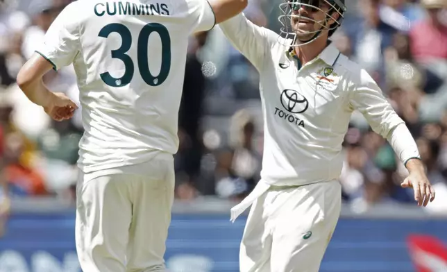 Australia's captain Pat Cummins, left, celebrates with teammate Travis Head after the dismissal of India's Ravichandran Ashwin during the day three of the second cricket test match between Australia and India at the Adelaide Oval in Adelaide, Australia, Sunday, Dec. 8, 2024. (AP Photo/James Elsby)