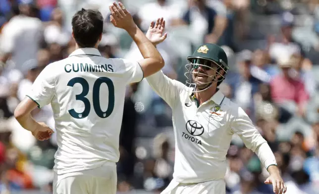 Australia's captain Pat Cummins, left, celebrates with teammate Travis Head after the dismissal of India's Ravichandran Ashwin during the day three of the second cricket test match between Australia and India at the Adelaide Oval in Adelaide, Australia, Sunday, Dec. 8, 2024. (AP Photo/James Elsby)