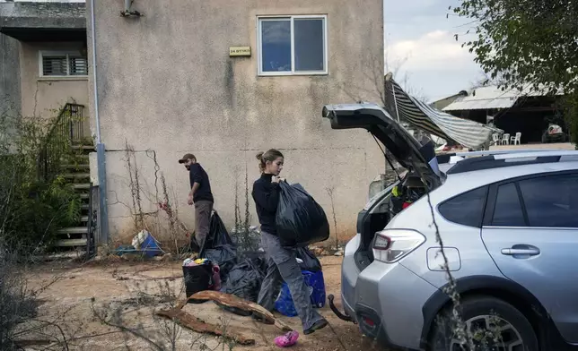 Shaked Malka, center, and her partner Yair Amar collect items from their home in Metula, Israel's northernmost town, on Wednesday, Dec. 4, 2024. Most residents of Israeli settlements and towns near the border with Lebanon have evacuated due to rocket attacks from Hezbollah in recent months.(AP Photo/Ohad Zwigenberg)