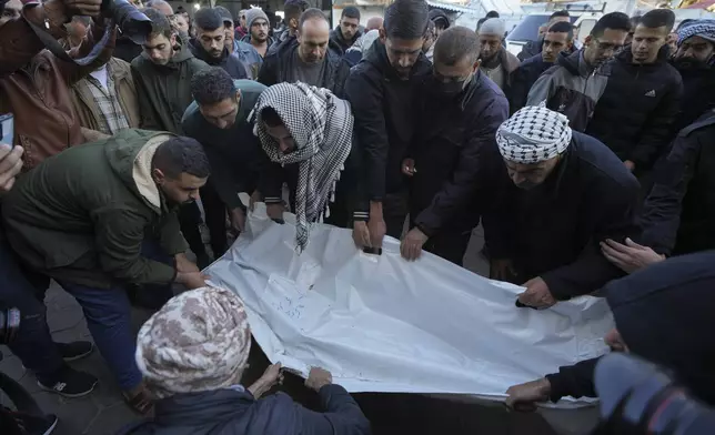 Palestinians carry the body of victim of an overnight Israeli strike, outside a hospital in Deir al-Balah, Gaza Strip, Wednesday, Dec. 4, 2024. (AP Photo/Abdel Kareem Hana)