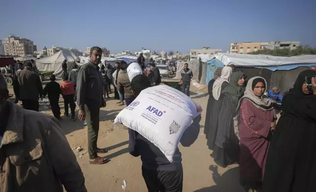 A man carries a sack of donated flour distributed by UNRWA at the Nuseirat refugee camp, Gaza Strip, Tuesday Dec. 3, 2024.(AP Photo/Abdel Kareem Hana)