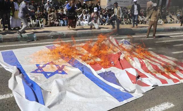 Yemeni graduates of fighting courses organised by Houthi group, burn Israeli British and American flags in support of Gaza during a parade, in Sanaa, Yemen, Wednesday, Dec. 4, 2024. (AP Photo/Osamah Abdulrahman)