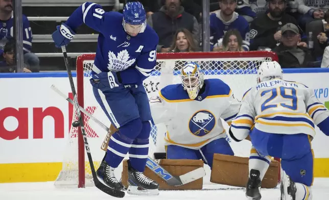 Toronto Maple Leafs forward John Tavares (91) tries to tip a shot in front of Buffalo goalie Devon Levi (27) during the first period of an NHL hockey game in Toronto, Sunday, Dec. 15, 2024. (Frank Gunn/The Canadian Press via AP)
