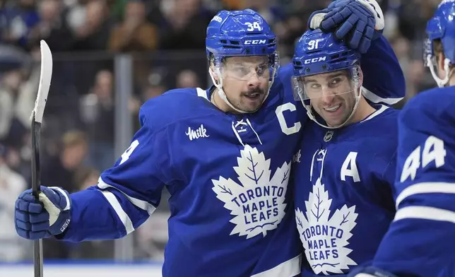 Toronto Maple Leafs center John Tavares (91) celebrates after his goal against the Buffalo Sabres with teammates Auston Matthews (34) and Morgan Rielly (44) during second-period NHL hockey game action in Toronto, Sunday, Dec. 15, 2024. (Frank Gunn/The Canadian Press via AP)