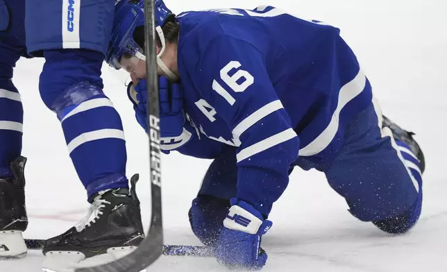 Toronto Maple Leafs forward Mitch Marner (16) drops to the ice after taking a puck to the face during first-period NHL hockey game action against the Buffalo Sabres in Toronto, Sunday, Dec. 15, 2024. (Frank Gunn/The Canadian Press via AP)