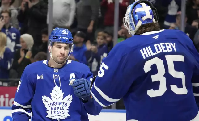 Toronto Maple Leafs center John Tavares (91) celebrates after his third goal of an NHL hockey game with teammate Dennis Hildeby (35) during late third-period action against the Buffalo Sabres in Toronto, Sunday, Dec. 15, 2024. (Frank Gunn/The Canadian Press via AP)