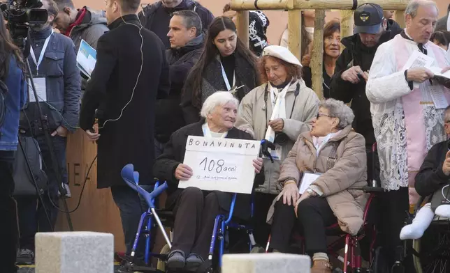 A woman holds a placard reading: "Welcome, 108 year's old the eldest of Ajaccio" as she waits for the arrival of Pope Francis at the Baptistery of St. Jean in Ajaccio during the Pontiff one-day visit in the French island of Corsica, Sunday, Dec. 15, 2024. (AP Photo/Alessandra Tarantino)