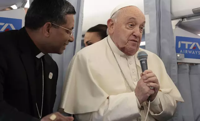 Pope Francis greets the journalists aboard his flight bound for Corsica for his apostolic journey in Ajaccio, Sunday, Dec. 15, 2024. (Remo Casilli/Pool Via AP)