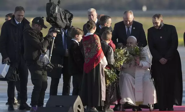 Pope Francis is welcomed by children as he arrives at Ajaccio International Airport on the occasion of his one-day visit in the French island of Corsica, Sunday, Dec. 15, 2024. (AP Photo/Alessandra Tarantino)