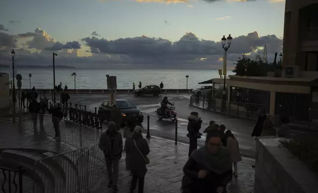 People walk near the seafront of Ajaccio prior to Pope Francis' visit, in the southern French island of Corsica, Saturday, Dec. 14, 2024. (AP Photo/Thibault Camus)