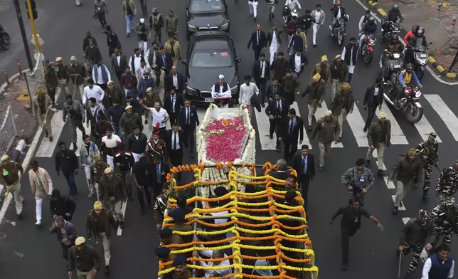 Security officials and others walk with the hearse carrying the body of former Indian Prime Minister Manmohan Singh towards the cremation site in New Delhi, India, Saturday, Dec. 28, 2024. (AP Photo)