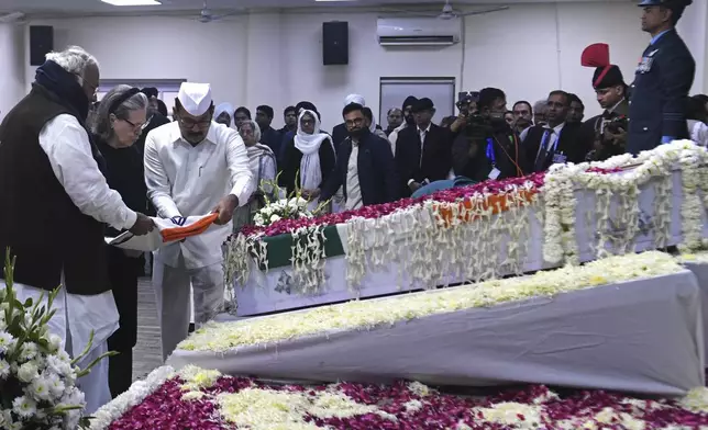 Congress party President Mallikarjun Kharge, left, and senior leader Sonia Gandhi are helped by an aide to place a flag on the casket of former Indian Prime Minister Manmohan Singh at their party headquarters in New Delhi, India, Saturday, Dec. 28, 2024. (AP Photo)